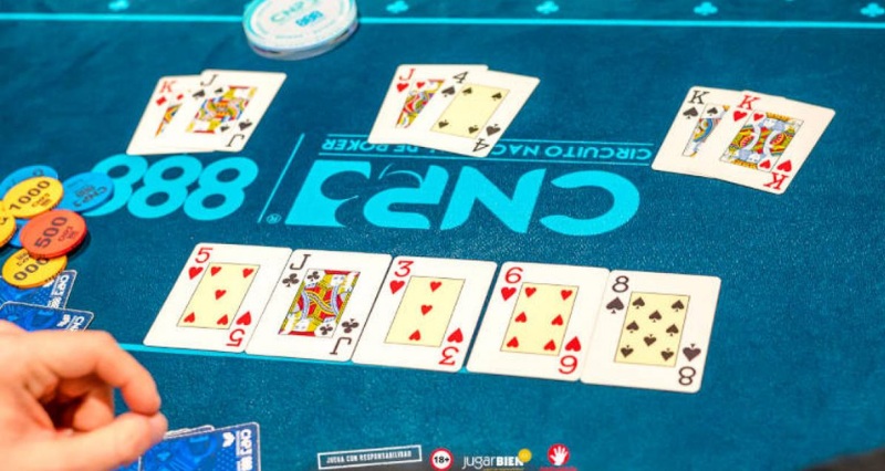 نمای نزدیک از کارت‌ها روی میز پوکر زنده همراه با چیپ‌ها و برد کامل